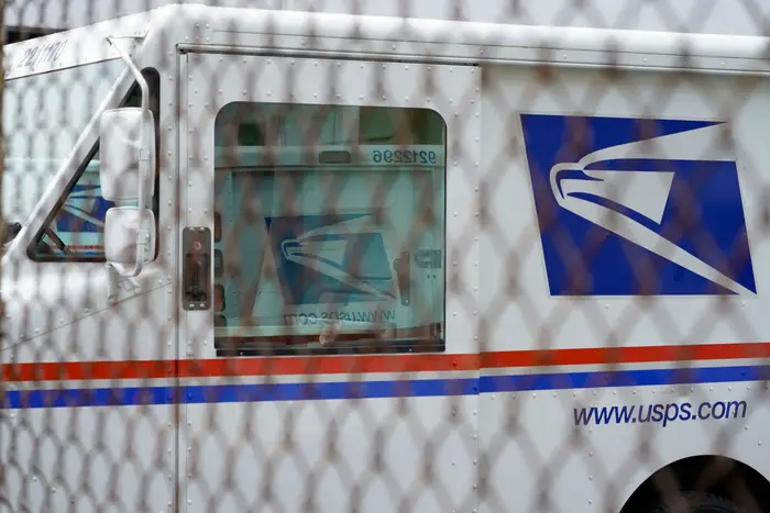A USPS truck behind a chainlink fence